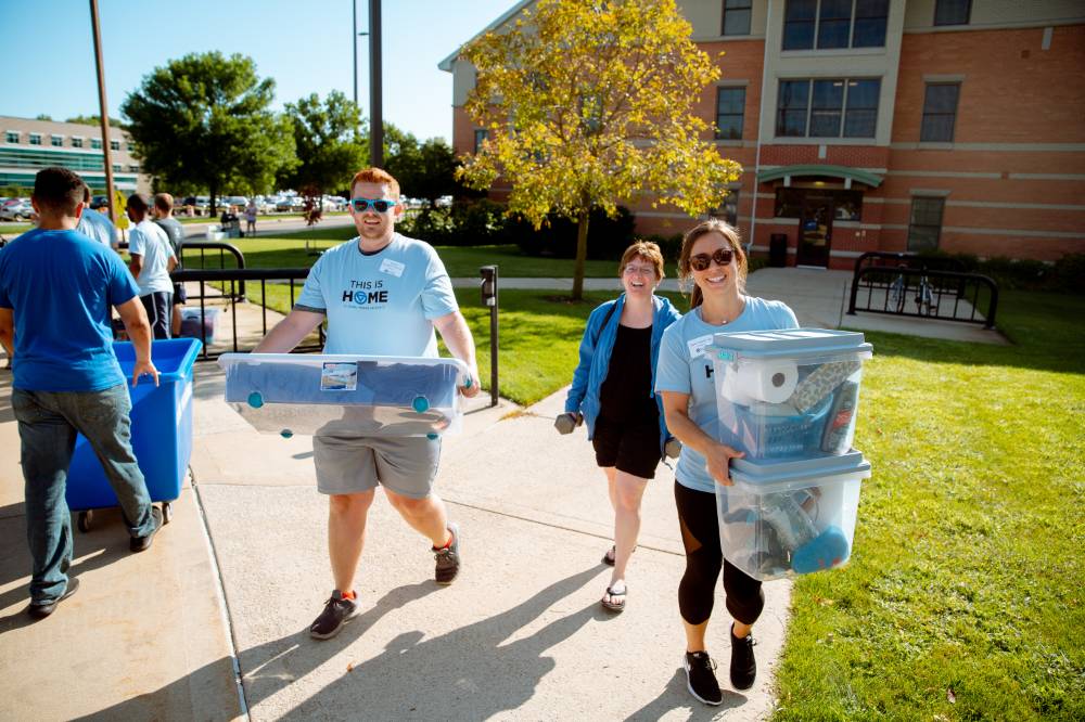 three people moving bins into the honors college